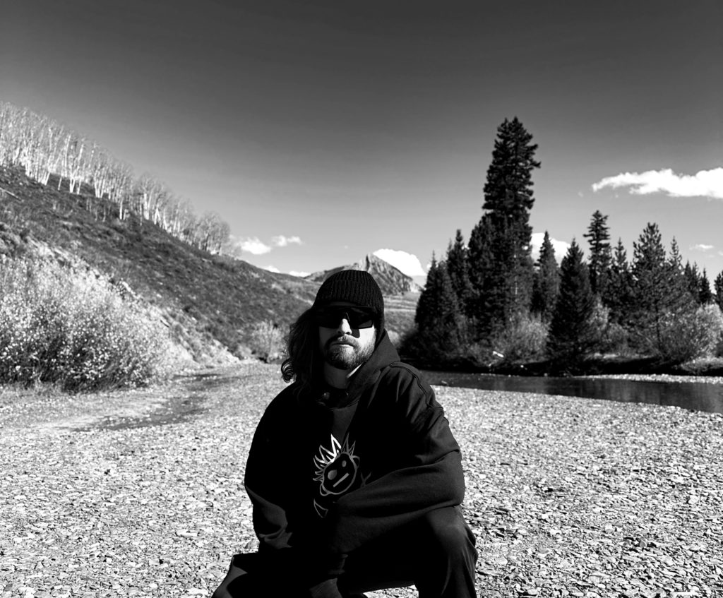 Colorado Bass Music Artist Bassiah with Crested Butte Mountain behind him.